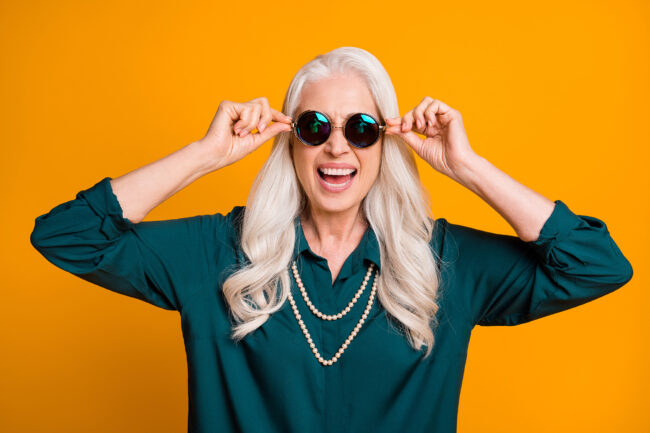 Photo of pretty cheerful white haired grandma lady music lover senior party active way of life cool look wear green shirt sun specs necklace isolated bright yellow color background