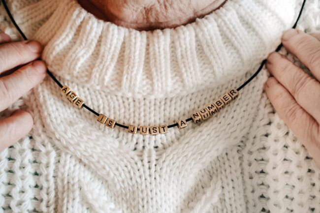 All ages matters, age is just a number, older population, young at heart, senior people. Senior female hands holding beads with text Age is just a number