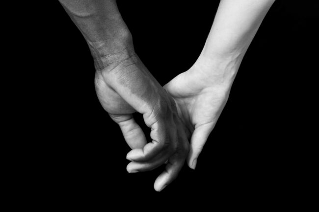 A hands of black man and white woman on black background