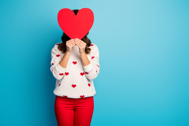 Portrait of her she nice attractive fashionable playful girl wearing festal clothes holding in hands heart closing face hiding congrats isolated on bright vivid shine vibrant blue color background
